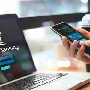 Hands holding a smartphone and laptop for online banking.